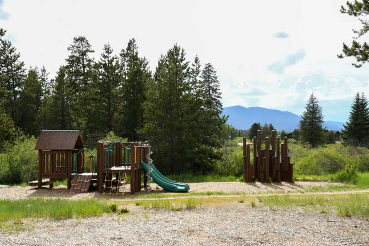 Here, a vibrant playground structure is nestled among trees, with slides and climbing apparatus designed for children and families. The atmosphere is energetic and welcoming, ideal for fun and outdoor play.