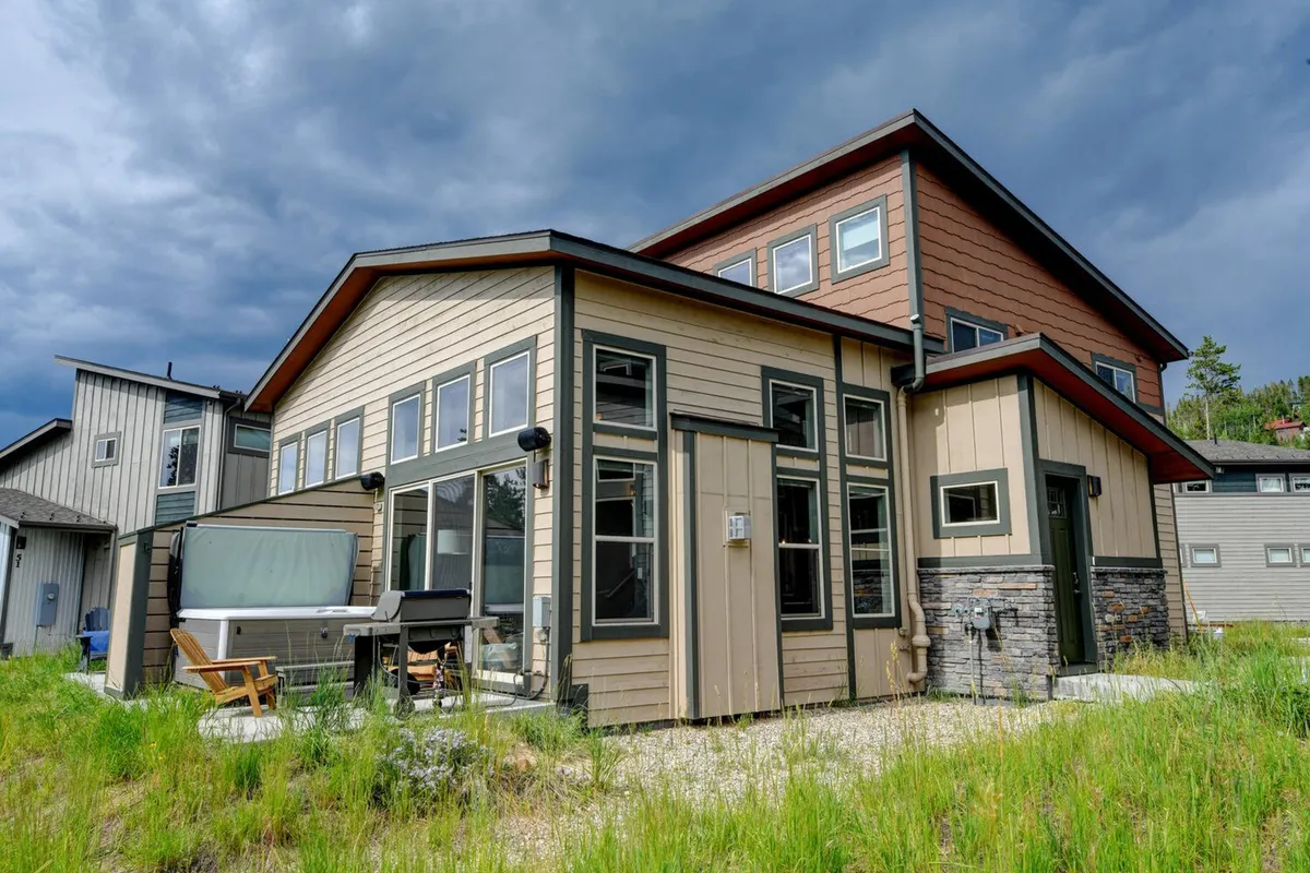 A modern exterior with large windows, a spacious deck area with seating, and landscaped gardens. The setting feels welcoming and serene, perfect for outdoor dining, relaxing with pets, or enjoying the sunset from the patio.